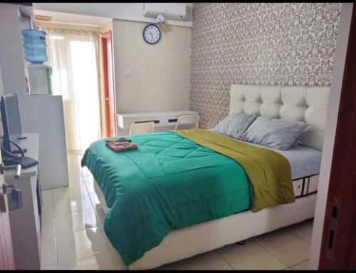 a bedroom with a bed and a clock on the wall at Japlen Room in Pondokcabe Hilir