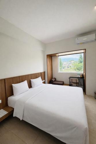 a bedroom with a large white bed and a window at Bogorienze City Resort in Pamoyanan