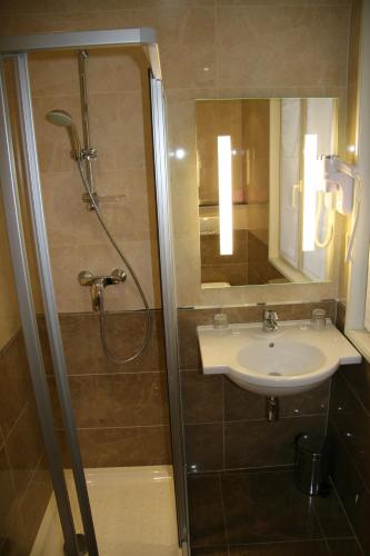 a bathroom with a shower and a sink and a mirror at Hotel Bellevue Saint-Lazare in Paris