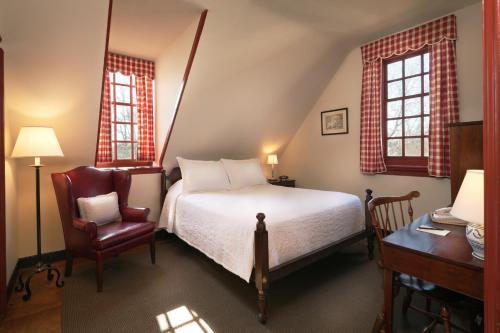 a bedroom with a bed and a chair and a desk at Colonial Houses, an official Colonial Williamsburg Hotel in Williamsburg