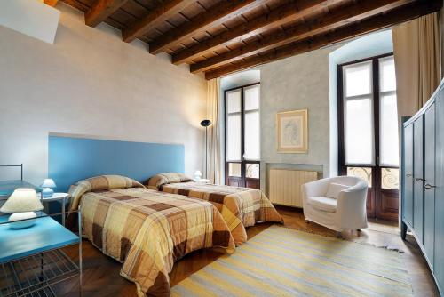 una habitación de hotel con 2 camas y una silla en Casa Marta, en Bérgamo