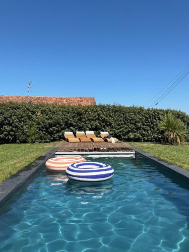 a swimming pool with chairs and umbrellas in it at Villa Haizea proche Bidart in Ahetze