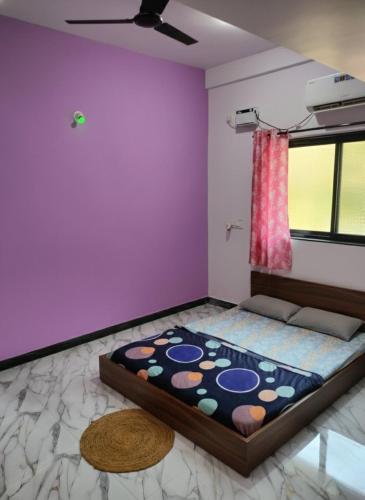 a room with a bed with a purple wall at Tree hugs mandrem in Mandrem