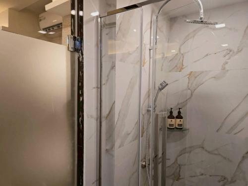 a bathroom with a shower with two bottles of wine at Casa Le Damuz At MRT Bangphlat - Adult Only in Bangkok