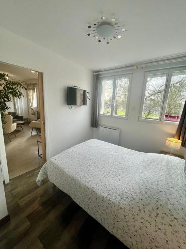 a white bedroom with a bed and a living room at gîte 65 m2 200 m gare t-g-v et fac 400 m centre-ville grand parking 250 places gratuit face au logement in Arras