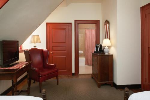 a bedroom with a red door and a chair and a desk at Colonial Houses, an official Colonial Williamsburg Hotel in Williamsburg