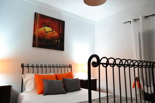 1 dormitorio con 1 cama con almohadas de color naranja y una pintura en Casinha das Flores, en Reguengos de Monsaraz