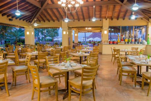 a dining room with tables and chairs and windows at Plaza Pelicanos Grand Beach Resort All Inclusive in Puerto Vallarta