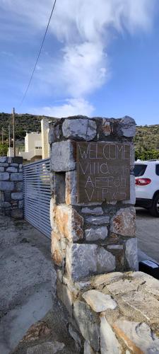 a sign on a stone wall with a building at Villa with Aegean views in Akhladherí