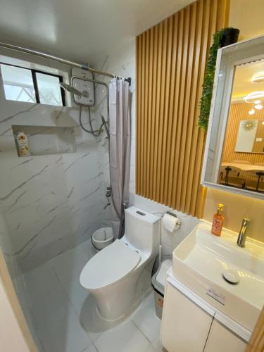 a bathroom with a white toilet and a sink at Urban Haven- Naga City in Naga