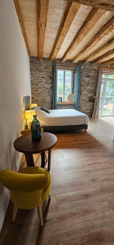 a bedroom with a bed and a table and chairs at Les Échappées Belles - Gîtes et chambres d'hôtes 4 étoiles in Antignac