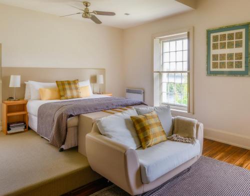 a bedroom with a bed and a couch and a window at The Woodbridge Waterfront Rooms in New Norfolk