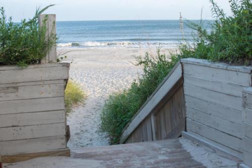 a wooden stairway leading to a beach with the ocean at Atlantic Beach Resort, a Ramada by Wyndham in Atlantic Beach