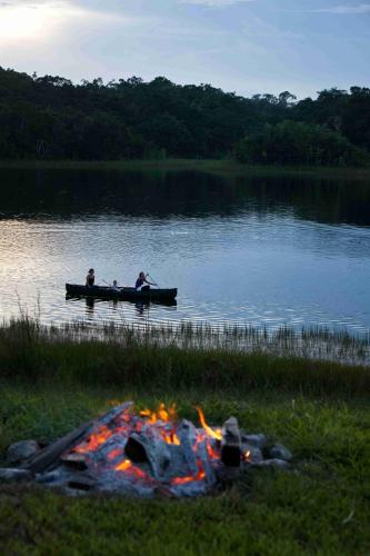two people are rowing a boat on a lake at Chan Chich Lodge in Gallon Jug