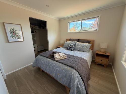 a bedroom with a bed and two windows at Grevillea Cottage in Murrumbateman
