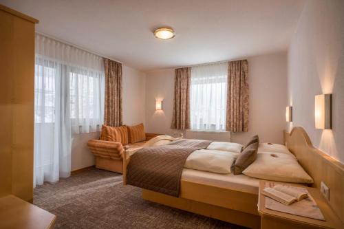 a hotel room with a bed and a couch and windows at Appartements Metzgerhof in Niederau