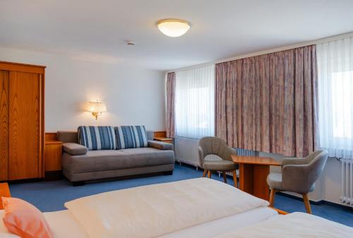 ein Hotelzimmer mit einem Bett und einer Couch in der Unterkunft Hotel Am Steinberg in Hildesheim