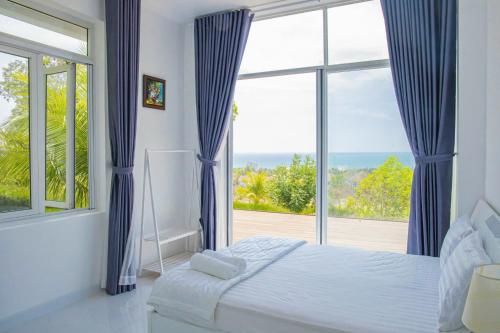 a bedroom with a bed and a large window at Căn Hộ OceanVista & Biệt Thự Sealink Phan Thiết - Mũi Né in Phan Thiet