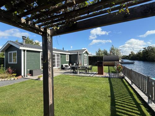 a view from the back yard of a house with a patio and water at NEW - Private Residence with Sauna - on a lake near Amsterdam in Vinkeveen