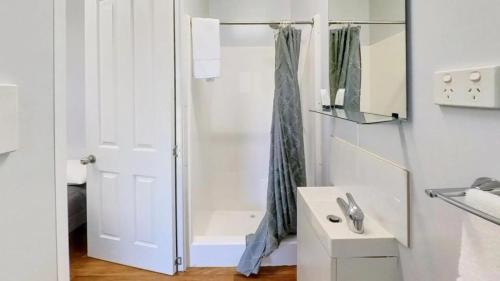 a white bathroom with a shower and a sink at Camden Holiday Park in Camden