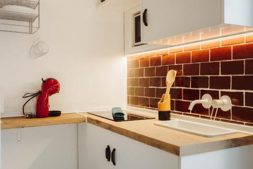 a kitchen with a sink and a red brick wall at Moscatel - Harbor's Light in Villajoyosa