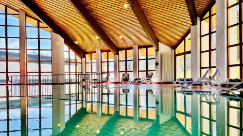 a swimming pool with chairs in a building with windows at Bernstein Landhaus Nordhelle in Meinerzhagen