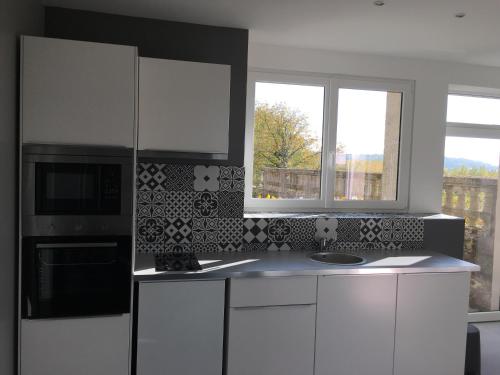 a kitchen with white cabinets and a microwave and windows at Belle vue in Montsoreau
