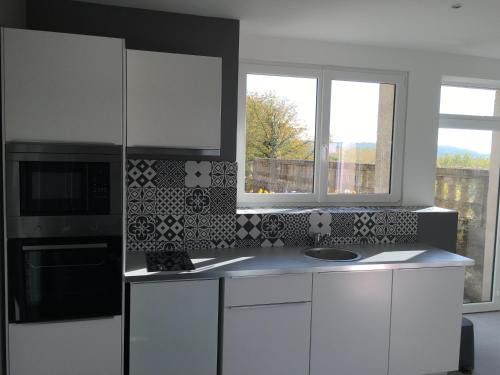 a kitchen with white cabinets and a microwave and two windows at Belle vue in Montsoreau