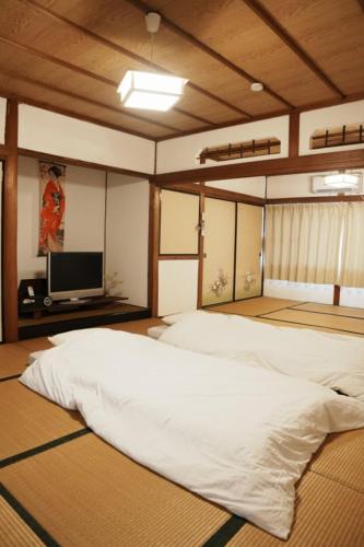 a bedroom with a large bed and a flat screen tv at 8人宿泊可 子供添い寝無料 1日1組限定で開放感のある90平米 吉野山天川村40分 奈良大阪1時間 駅から徒歩5分 家主居住型 大淀桜庵 in Oyodo
