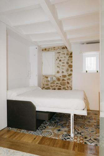 a bed in a room with a stone wall at Verdejo - Harbor's Light in Villajoyosa