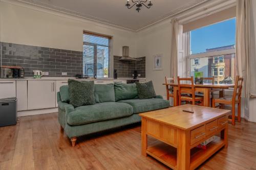 a living room with a green couch and a table at Stylish city view flat in mural quarter in Bristol