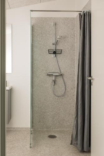a shower with a shower curtain in a bathroom at Storkesøen Ribe Holiday Cottages and Apartments in Ribe