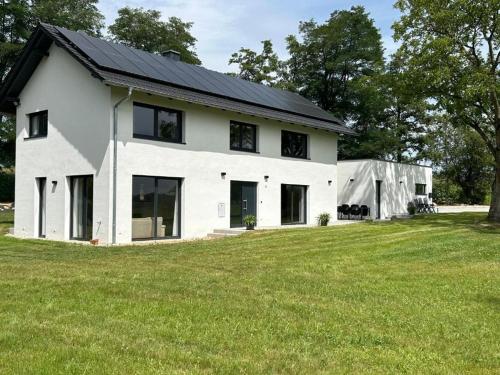 ein weißes Haus mit schwarzem Dach auf einem Grasfeld in der Unterkunft 23 Mattenham - Rückzugsort in Abgeschiedenheit in Vilshofen an der Donau