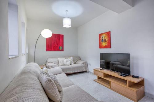 a living room with a couch and a flat screen tv at 1-Bed Suite Near Spinola Bay in Paceville