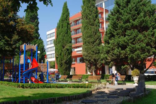 um parque com bancos e um parque infantil em frente a um edifício em Nesebar Vigo Panorama Private Studios em Nesebar
