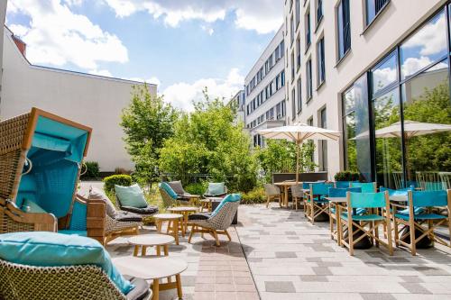a patio with chairs and tables and a building at Motel One Rostock in Rostock