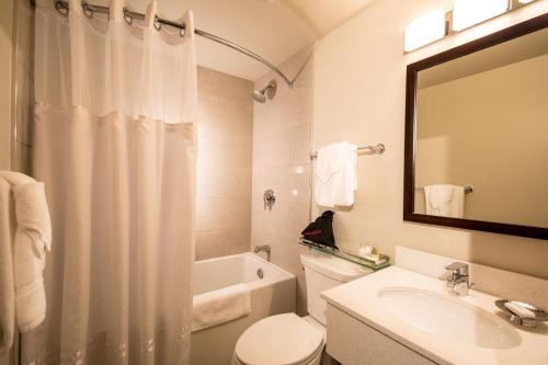 a bathroom with a sink and a toilet and a bath tub at Prestige Oceanview Hotel Prince Rupert in Prince Rupert
