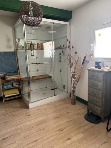 a glass cabinet in a room with a wooden floor at Chambre Le Colibri in Lezoux