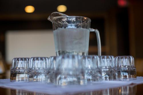 a jug of water sitting on a table with glasses at Prestige Oceanview Hotel Prince Rupert in Prince Rupert