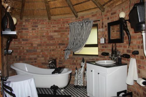 a bathroom with a white bath tub and a brick wall at Shamba Yetu Mountain Lodge in Maanhaarrand