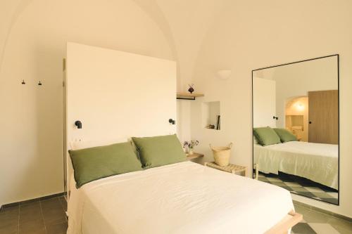 a bedroom with a white bed and a mirror at Masseria Pietra e Terra in Carovigno