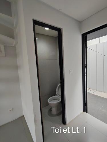 a bathroom with a toilet and a glass door at Park Serpong Type XYZ Cluster Charm in Carangpulang
