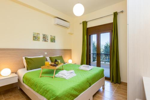a bedroom with a green bed and a balcony at Eleonas Apartments in Prinés