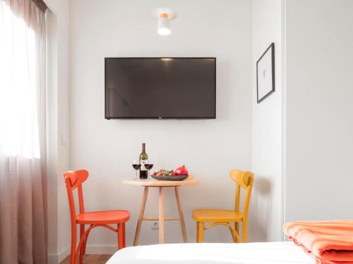 a room with a table with three chairs and a tv at LSA Restauradores by Numa in Lisbon