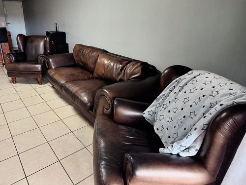 a brown leather couch sitting in a living room at Merve's Place - Portobelo 48 in Mossel Bay