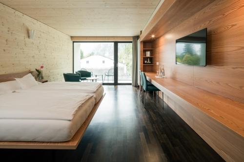 1 dormitorio con 1 cama y TV en la pared en Raselli Sport Hotel, en Poschiavo