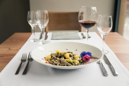 a white plate of food on a table with wine glasses at Raselli Sport Hotel in Le Prese, Poschiavo