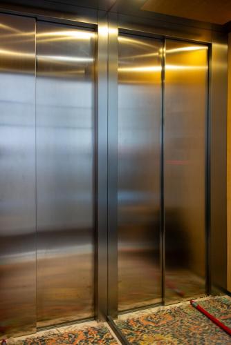 des portes d'ascenseur en métal dans une pièce avec un tapis dans l'établissement La Plâtrière, au Puy-en-Velay