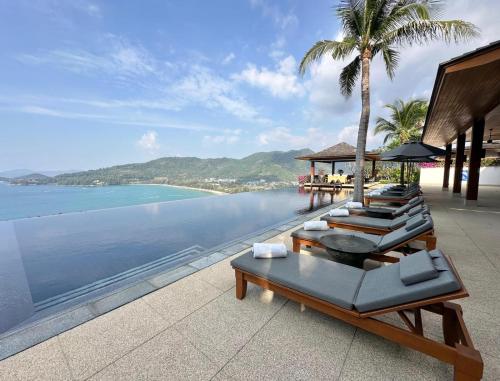 a row of lounge chairs on a beach with the ocean at Villa 29 Montebello Andara Resort Villas in Kamala Beach