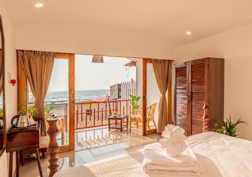 a bedroom with a bed and a balcony with the ocean at Ananas Beach Resort in Agonda